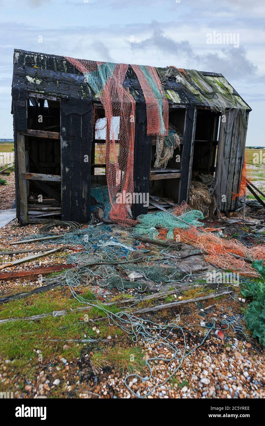 Alte verfallene Fischerhütte mit verlassenen Fischernetzen, am Dungeness Beach, Kent, England, UK Stockfoto