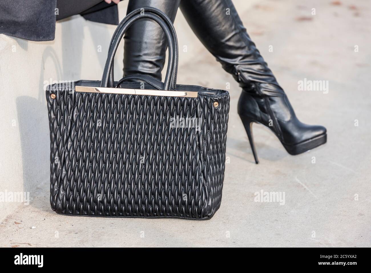 Modische schwarze Stiefel mit einer Handtasche. Stockfoto