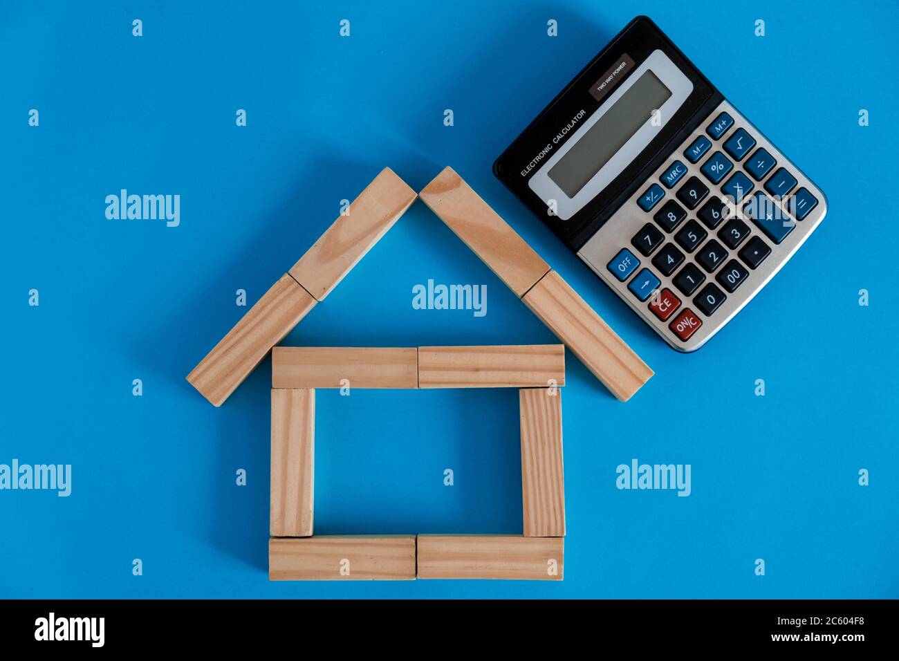 Nahaufnahme des Holzmodells und der Schlüssel mit Taschenrechner auf blauem Hintergrund. Hypothek Immobilien Versicherung kaufen Traum Haus Shopping Verkauf Miete Konzept. Wohnung lag Stockfoto