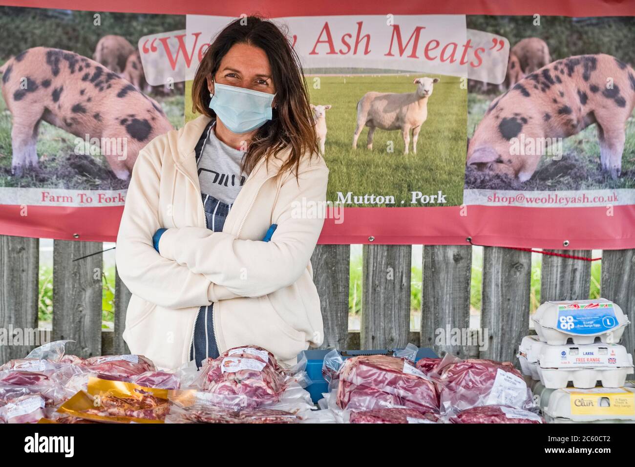 Rosario Foster trägt eine Gesichtsmask an ihrem Metzgerstand auf dem lokalen Lebensmittelmarkt in Presteigne, Wales, Großbritannien, die gerade nach Monaten der Sperre wieder geöffnet wurde Stockfoto