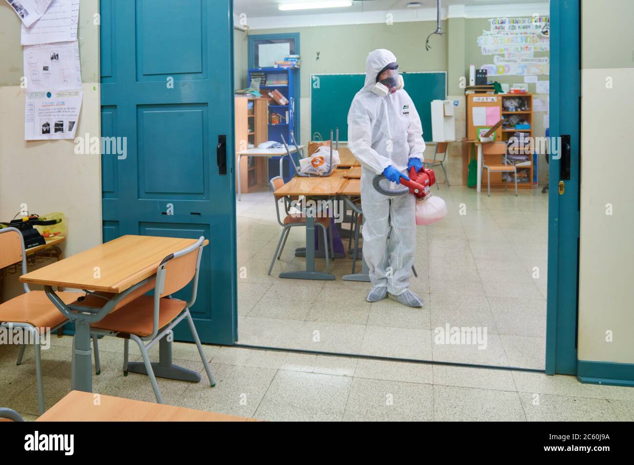 Arbeiter in Schutzanzug desinfizieren Innenraum der Schule. Stockfoto