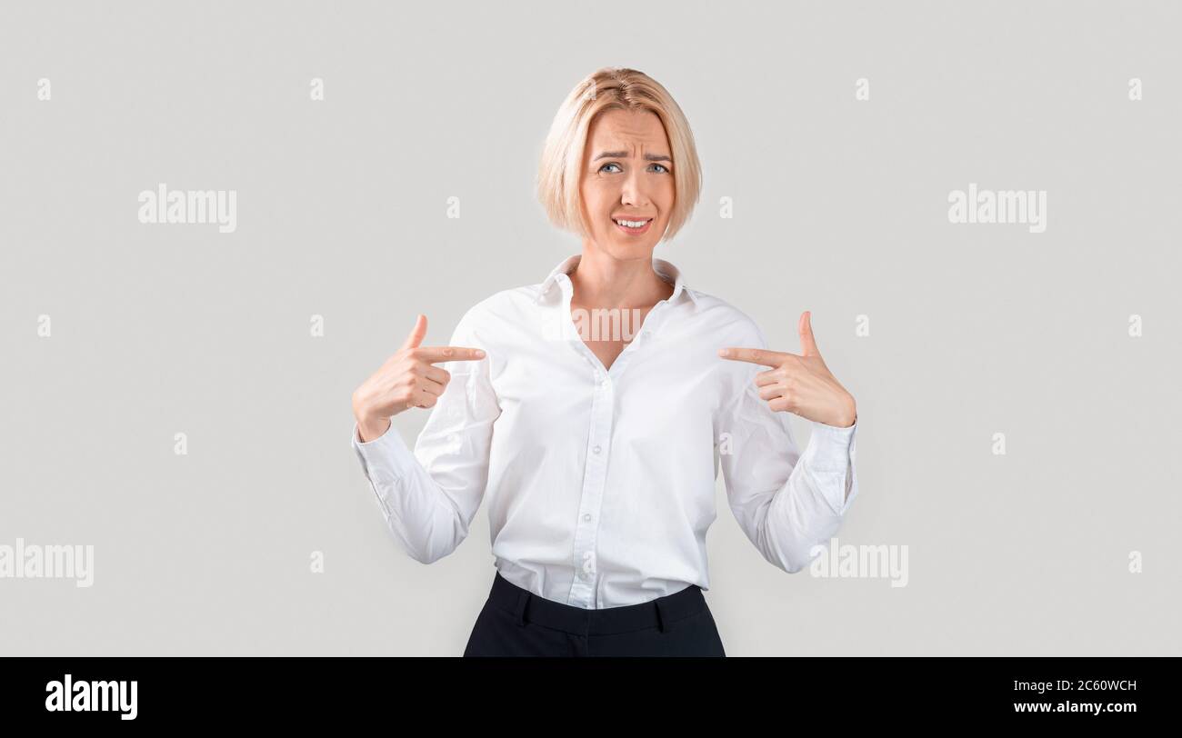 Alter. Reife Geschäftsfrau, die fragend auf sich zeigt, unzufrieden mit Nominierung oder Entlassung auf hellem Hintergrund Stockfoto