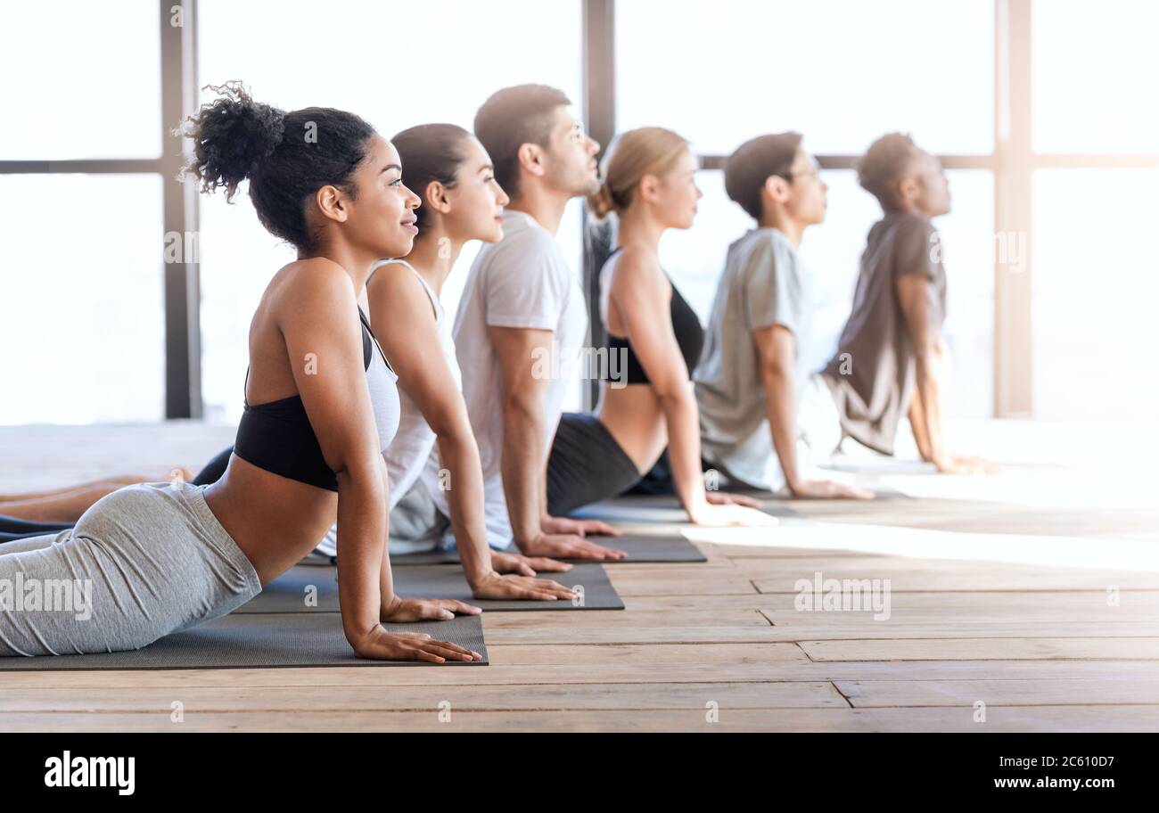 Yoga-Gruppenmitglieder, die Kobra Pose beim Training in modernen Loft-Studio Stockfoto