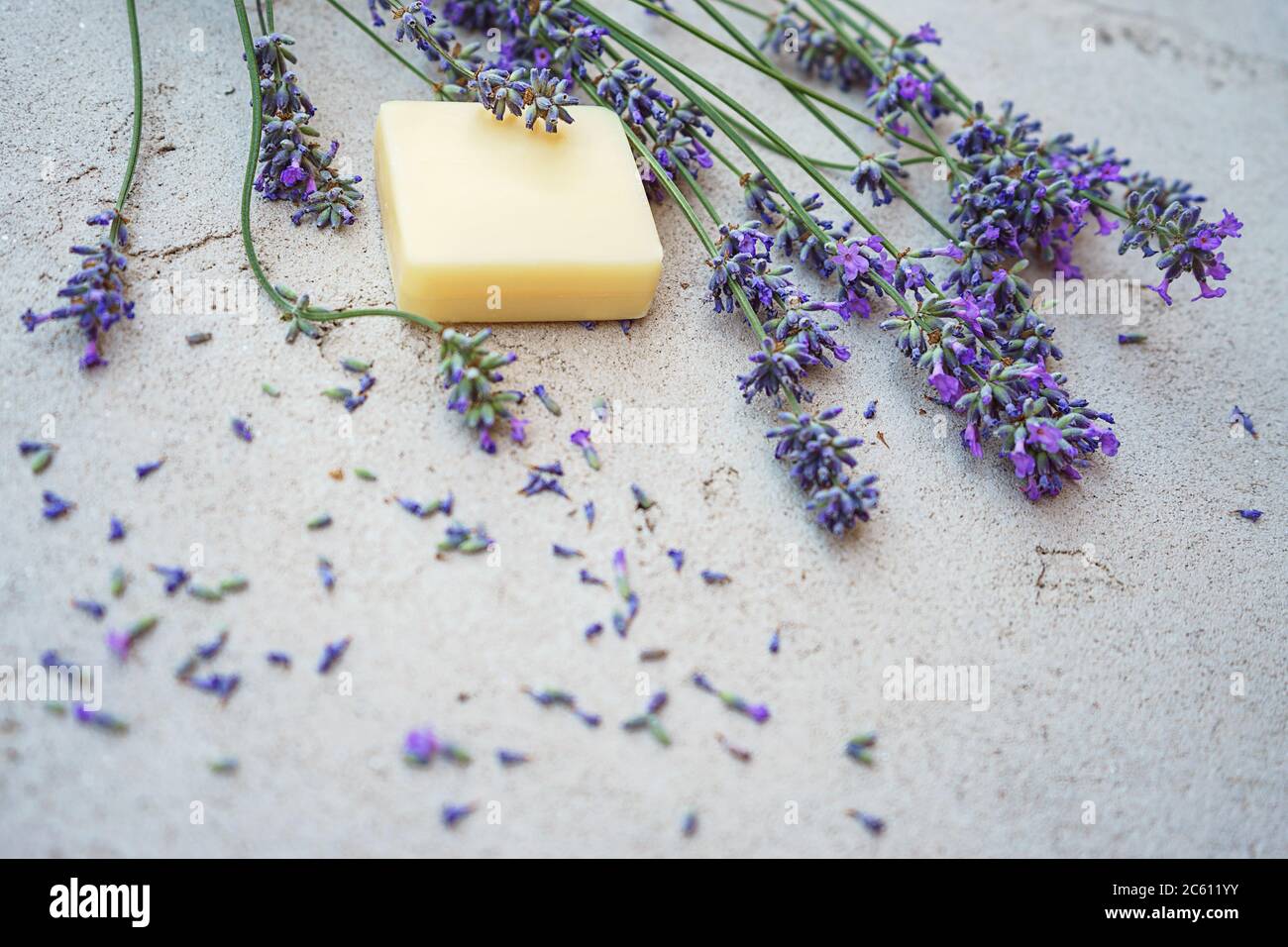 Lavendelblüten und natürliche Seife für die Körperpflege auf konkreten Hintergrund. Flach, Ansicht von oben. Kopieren Sie Platz. Stockfoto