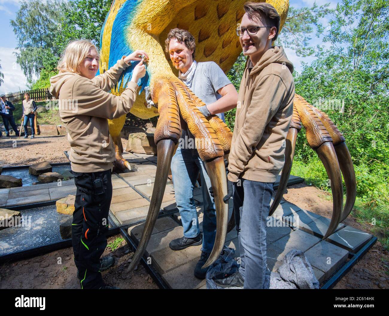 Rehburg Loccum, Deutschland. Juli 2020. Die Mitarbeiter Alessandro Stauf (l-r), Jens Kosch und Yannik Weber montieren im Münchehagen Dinopark eine große Klaue auf ein neues Modell eines Therizinosaurus. Der mehr als neun Meter lange Therizinosaurus hatte drei gigantische Krallen an jeder Hand, weshalb Forscher ihn als "Zythe Eidechse" bezeichneten. Kredit: Julian Stratenschulte/dpa/Alamy Live Nachrichten Stockfoto