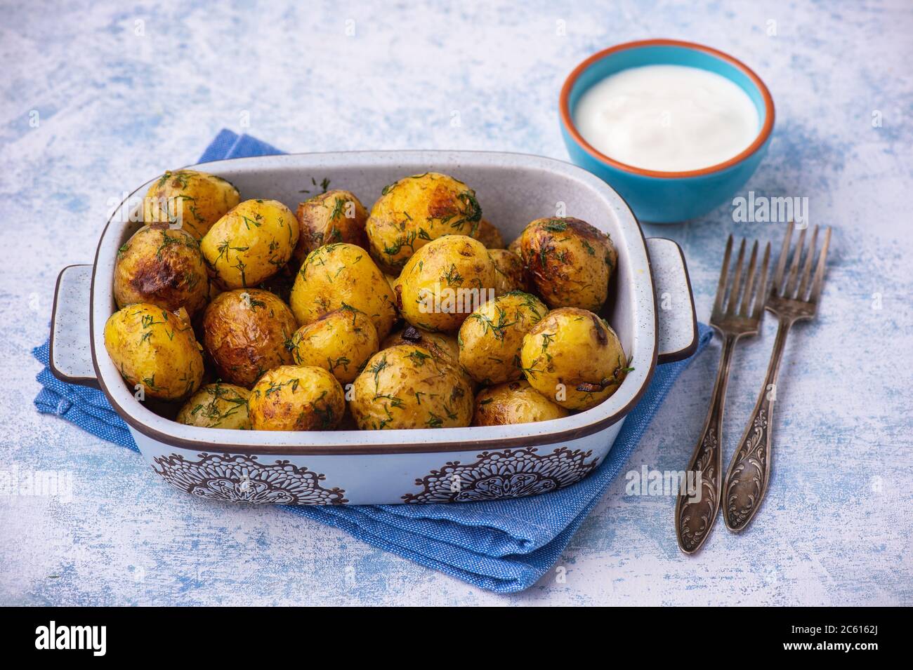 Gebratene Babykartoffeln mit Knoblauch und Kräutern., auf hellem Hintergrund. Stockfoto