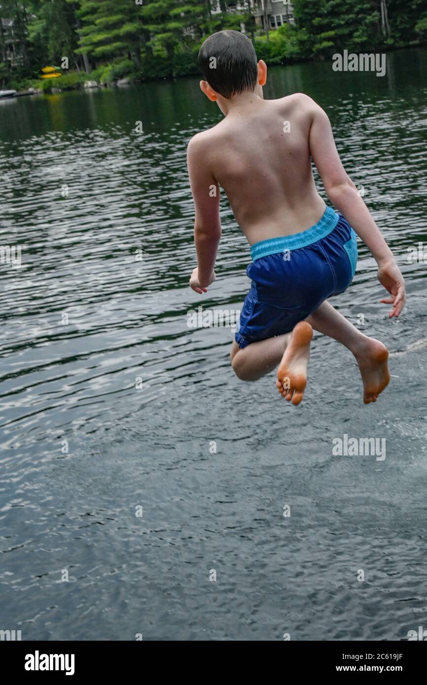 Teenager springt in einen See - Junge spielt in Lake Sunapee New Hampshire - Springen von einem See Dock / Steg in einen Teich Stockfoto