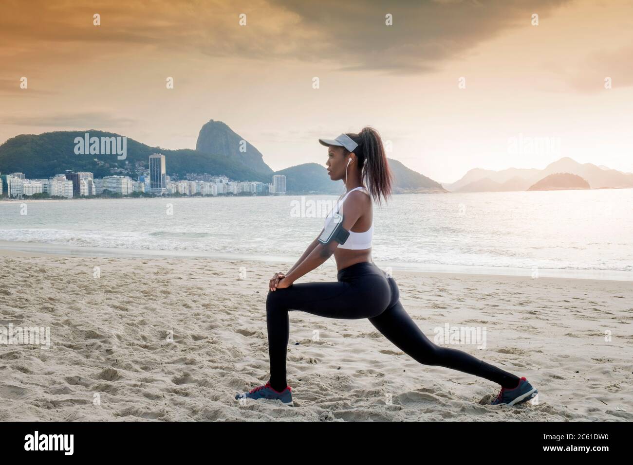 Südamerika, Brasilien, Copacabana Beach. Eine schwarze Brasilianerin in den frühen Dreißigern, die sich vor einem Lauf dehnt Stockfoto