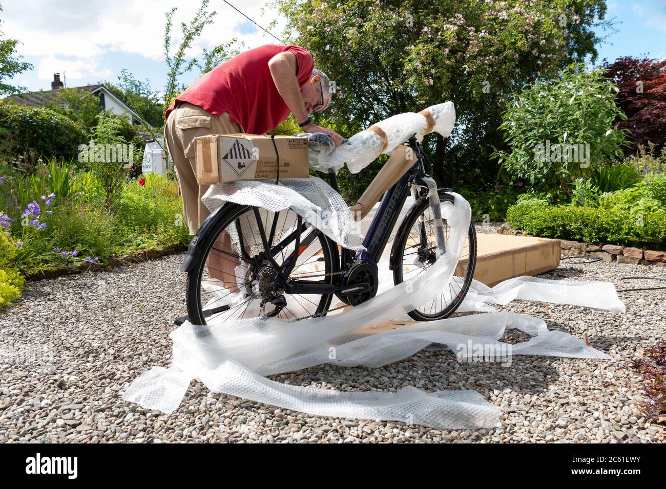 Home Lieferung von Elektro-Fahrrad eBike online bestellt während der Coronavirus Lockdown - Fahrrad aus Fahrradbox und Auspacken Luftpolsterfolie genommen - UK Stockfoto