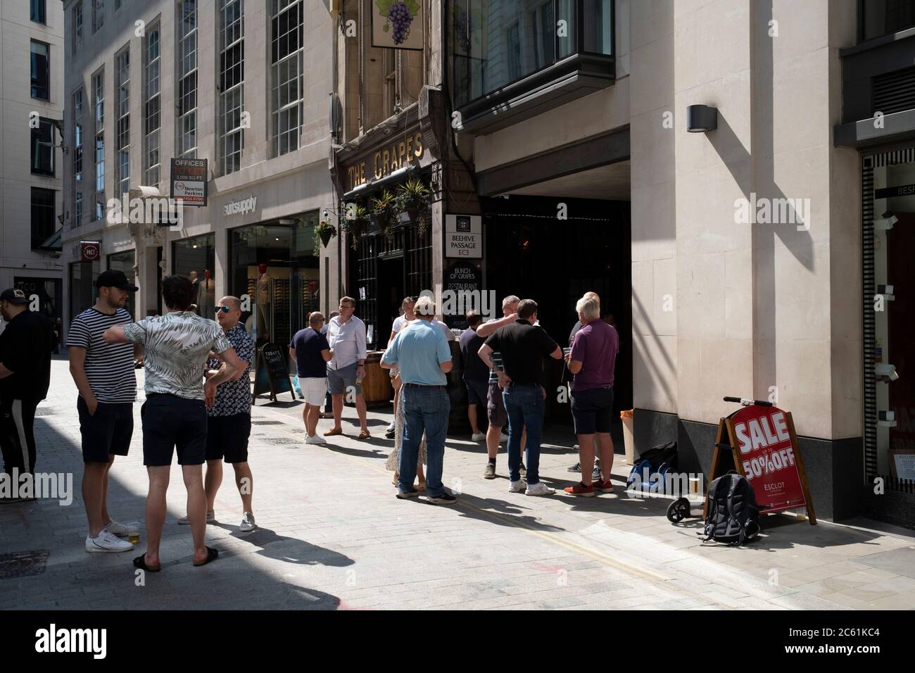 Am Tag, an dem bekannt gegeben wurde, dass die Maßnahmen zur Sperrung des Coronavirus noch weiter lockern werden, genießen Trinker vor einem Pub in der City of London am 23. Juni 2020 in London, England, Großbritannien, einige Take-Out-Drinks im Grapes Pub. Die Regierung hat ihre Sperrregeln gelockert und erlaubt ab Anfang Juli, dass Spuben wieder geöffnet werden, solange sie soziale Distanzierungssysteme eingerichtet haben. Stockfoto