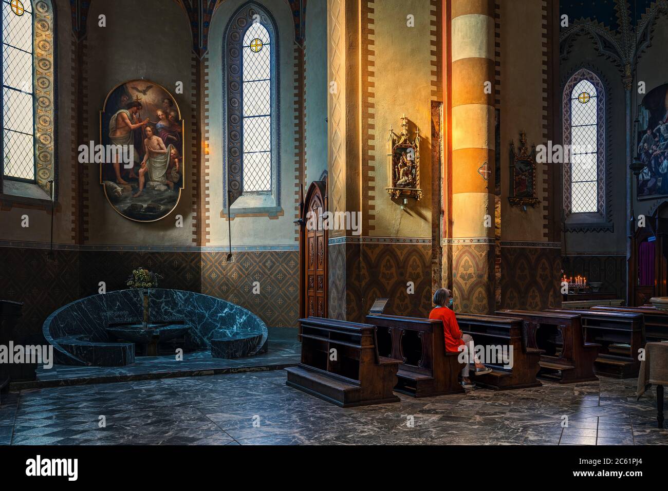 Frau auf Holzblatten im Inneren von San Lorenzo - einer römisch-katholischen Kathedrale, auch bekannt als Duomo, der dem Heiligen Lorenz in Alba, Italien, gewidmet ist. Stockfoto