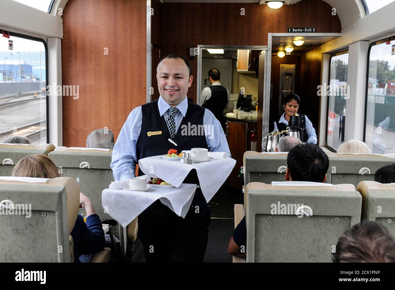 Ein Mitarbeiter im Restaurant und im Auto, der eine warme Mahlzeit an Bord des Rocky Mountaineer-Zuges in British Columbia, Kanada, serviert Stockfoto