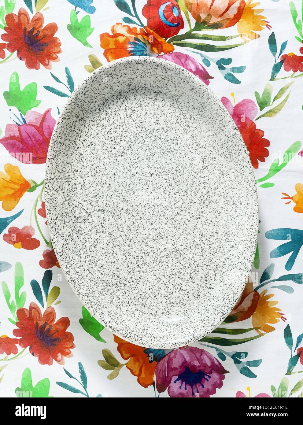 Leere ovale Schale auf einer hellen bunten Tischdecke Stockfoto