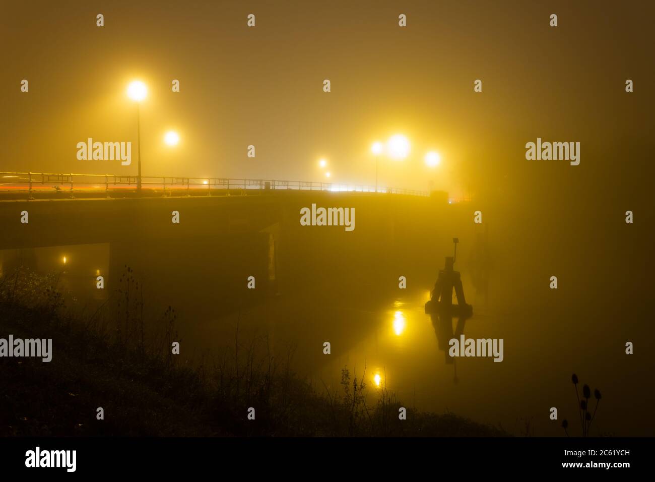 Brücke beleuchtet von Straßenlaternen am Abend mit dichtem Nebel Stockfoto