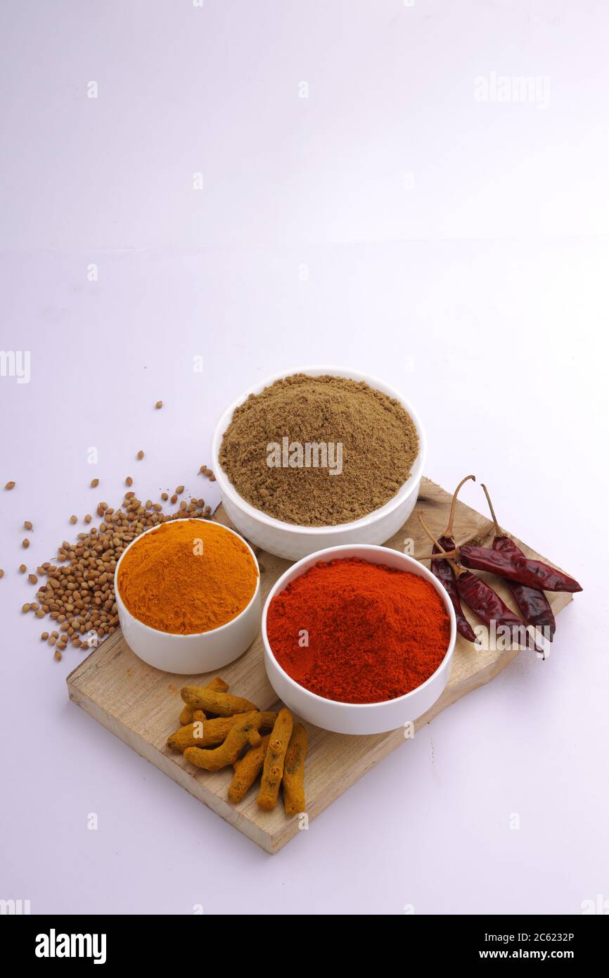 Indische Gewürze Chili, Kurkuma und Koriander sind die drei grundlegenden Gewürze für indische Curry oder Gerichte, in einer weißen Schüssel angeordnet Stockfoto