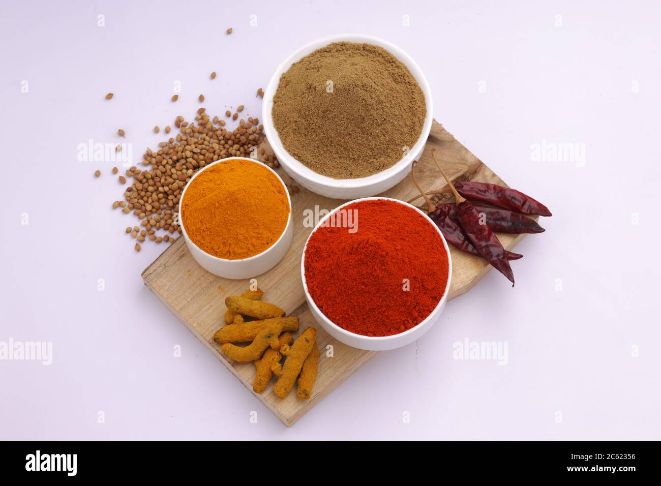 Draufsicht auf indische Gewürze Chili, Kurkuma und Koriander sind die drei Grundgewürze, die für indisches Curry oder Gerichte verwendet werden, in weißen Schalen angeordnet Stockfoto