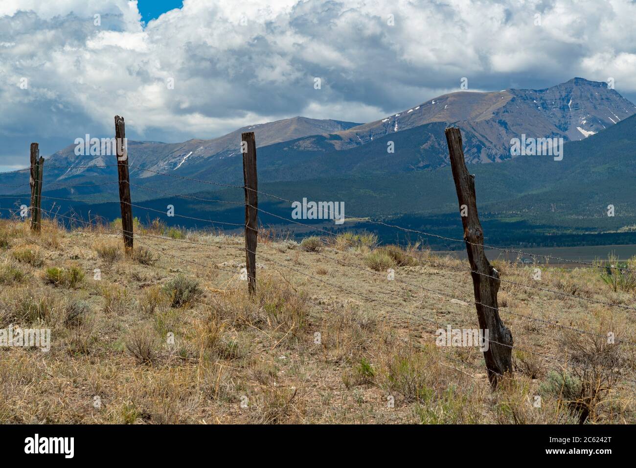 Alt abgenutzter, verwitterter Stacheldrahtzaun mit felsigen Bergen, Colorado, USA Stockfoto