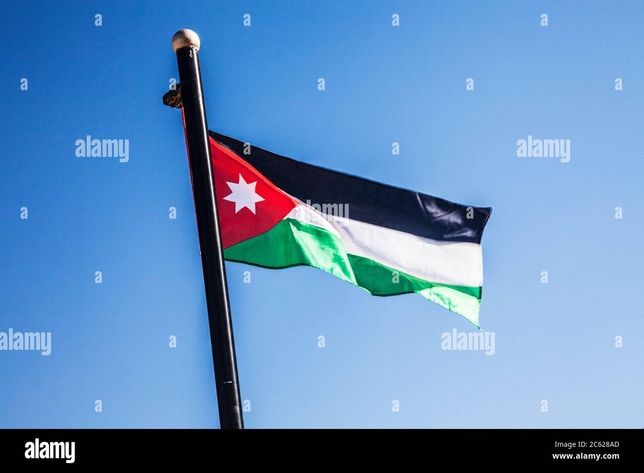 Eine jordanische Flagge flattert in der Brise gegen einen Sommerhimmel. Stockfoto