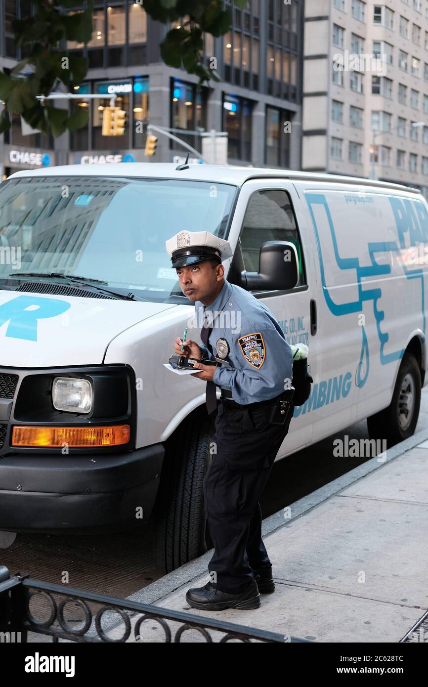 NYPD Verkehrsbeauftragter gesehen Ausstellung eines Parkscheins an einen Van als hat seine Zeitperiode in einem belebten NYC überschritten. Stockfoto