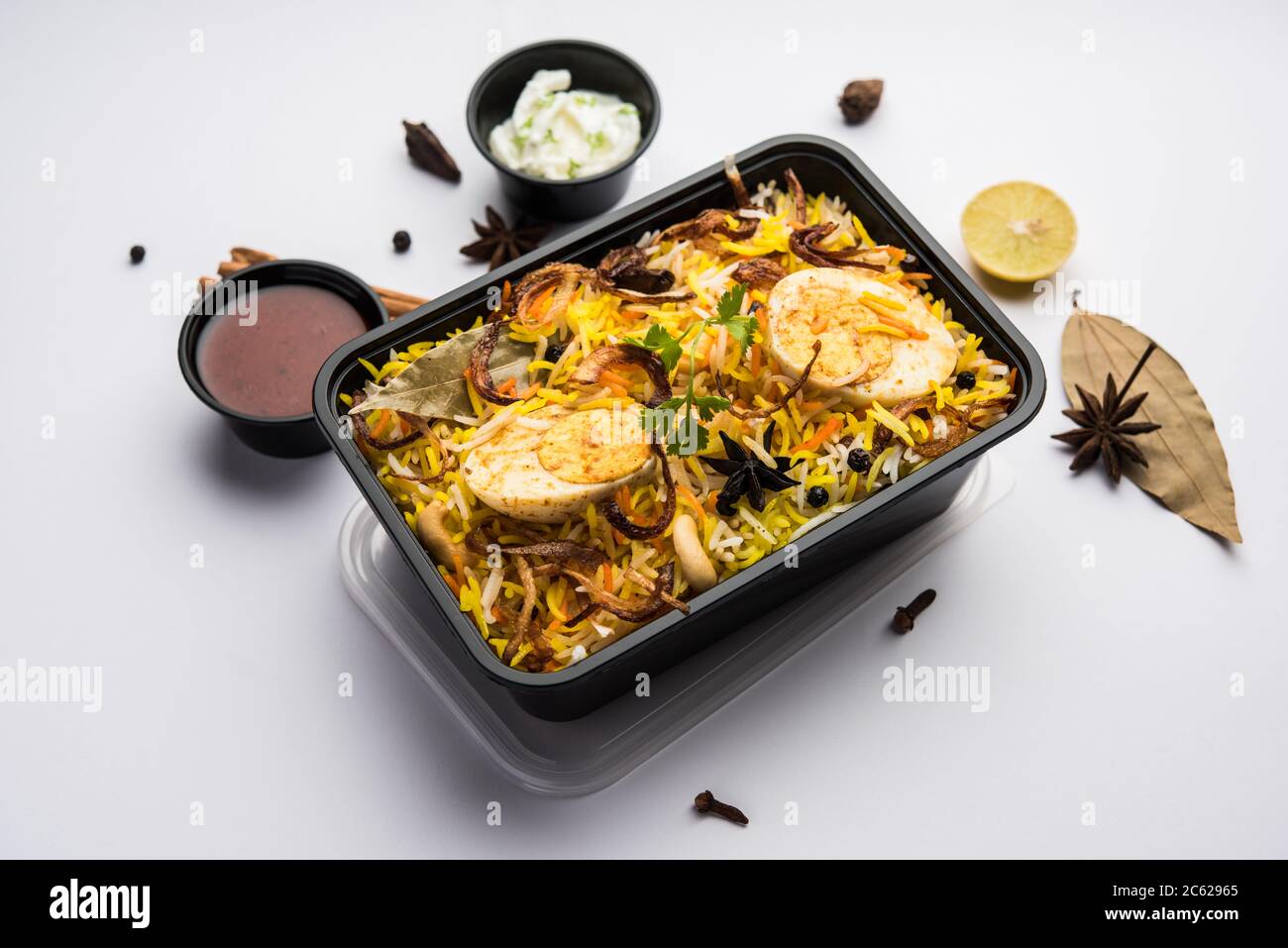 Restaurant Stil Ei Biryani oder Anda Pulao verpackt für die Hauslieferung in Plastikbox oder Container mit Raita und Salan Stockfoto