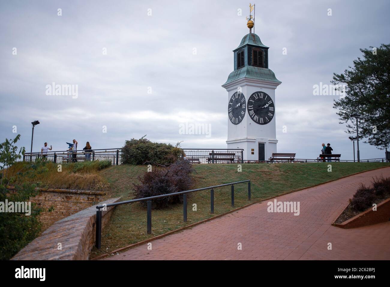 Novi Sad, Serbien, 23. Jun 2020: Besucher an einem Aussichtspunkt der Festung Petrovaradin neben einem Uhrenturm Stockfoto
