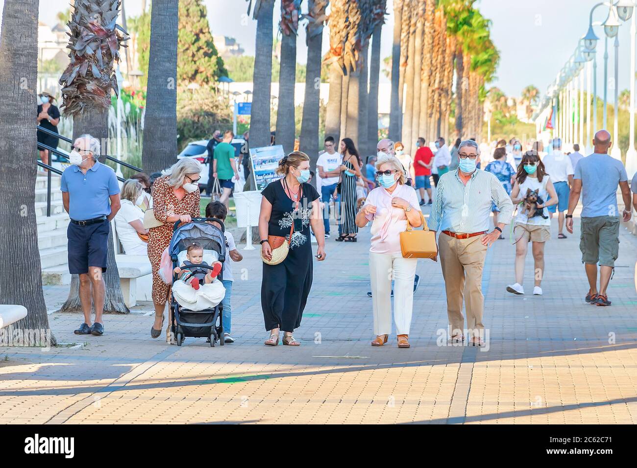 Huelva, Spanien - 3. Juni 2020: Menschen, die bei Sonnenuntergang an der Islantilla Promenade entlang gehen, tragen eine Schutzmaske wegen Covid-19. Stockfoto