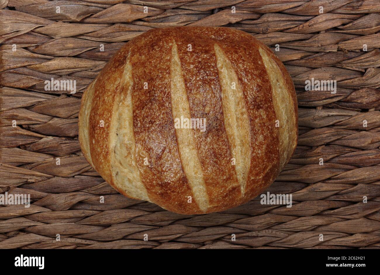 Luftaufnahme eines ganzen Sauerteig Brot auf einem Korbhintergrund mit Kopierraum auf der linken Seite Stockfoto