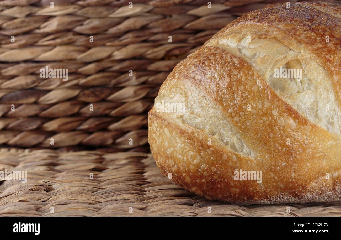 Seitenansicht eines Sauerteig-Laibs Brot auf einem Korbhintergrund mit Kopierraum auf der linken Seite Stockfoto