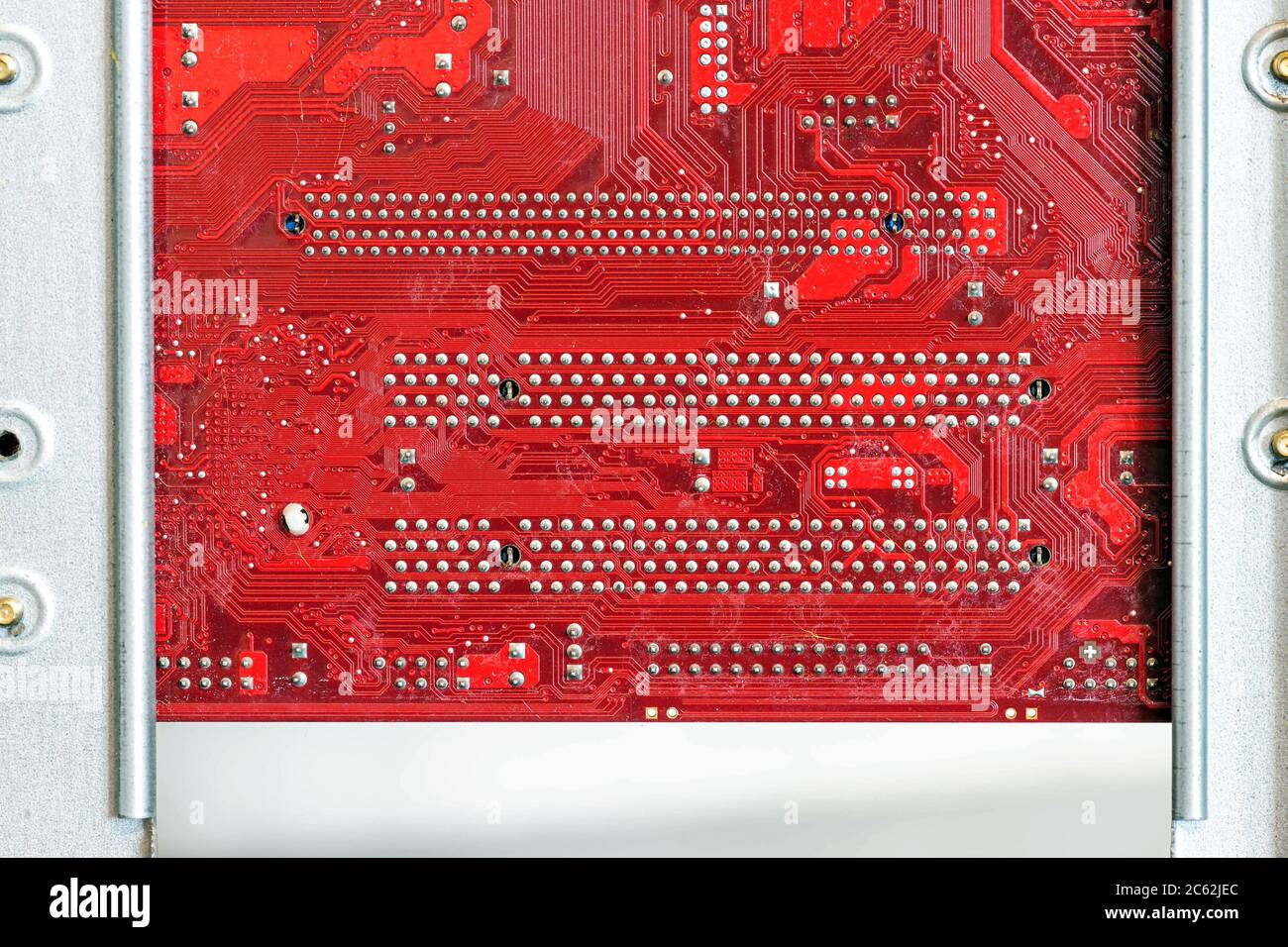 Rote Computerplatine, die mit dem Gehäuse verbunden ist. Hardwarekomponenten. Blick in den Innenraum, Hintergrund, Nahaufnahme Stockfoto