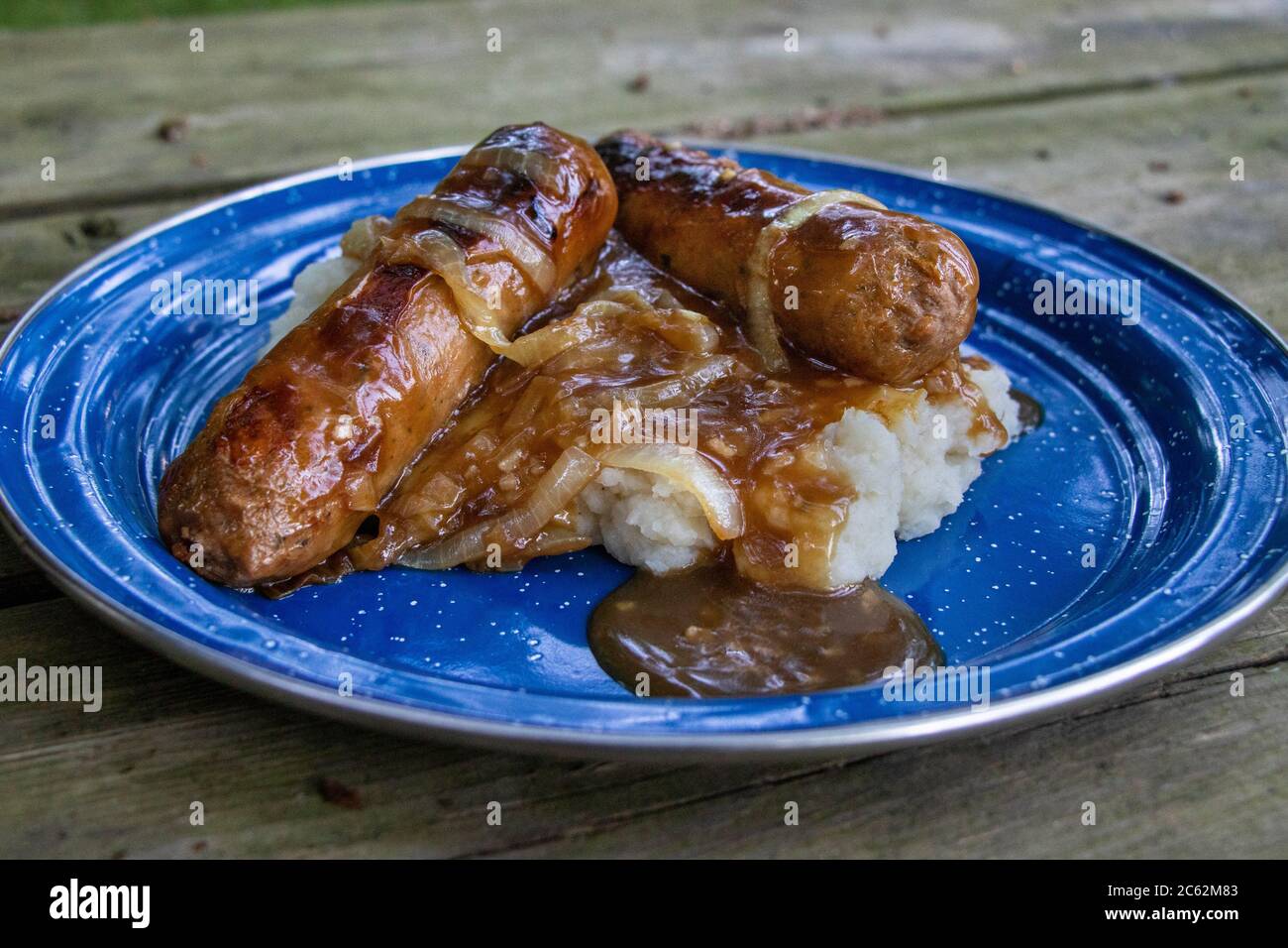 Vegane Bangers & Mash mit Fleischwürsten, Soße, Kartoffelpüree in einer Camping-Emaille-Platte, Abendessen Stockfoto