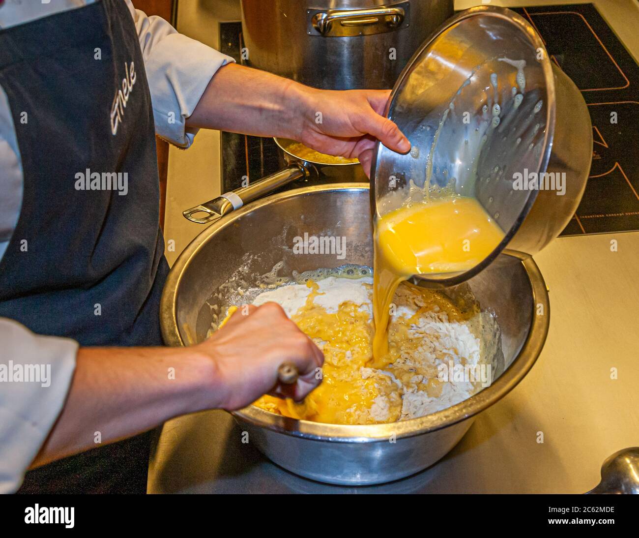 Der Knöpfler in Aktion. Kässpätzler werden auch Käsknöpfle genannt. Frische Pasta mit Reibe - typisch österreichische Käsepasta - Teig fällt in kochendes Wasser Stockfoto