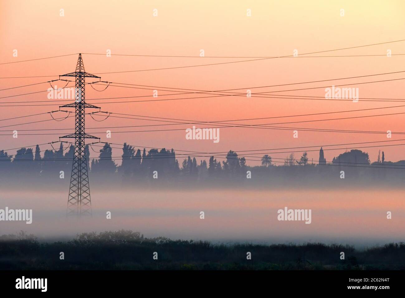 Sendeturm, der bei Sonnenaufgang aus dem Nebel auftaucht Stockfoto
