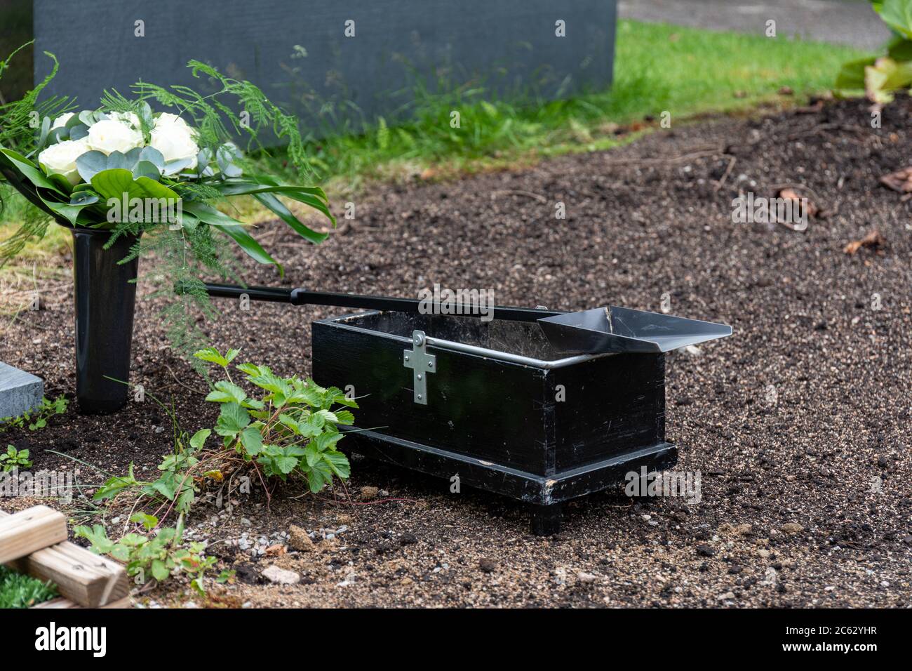 Schaufel und der kleine Kasten des Sandes vom frischen Grab auf dem Friedhof Stockfoto