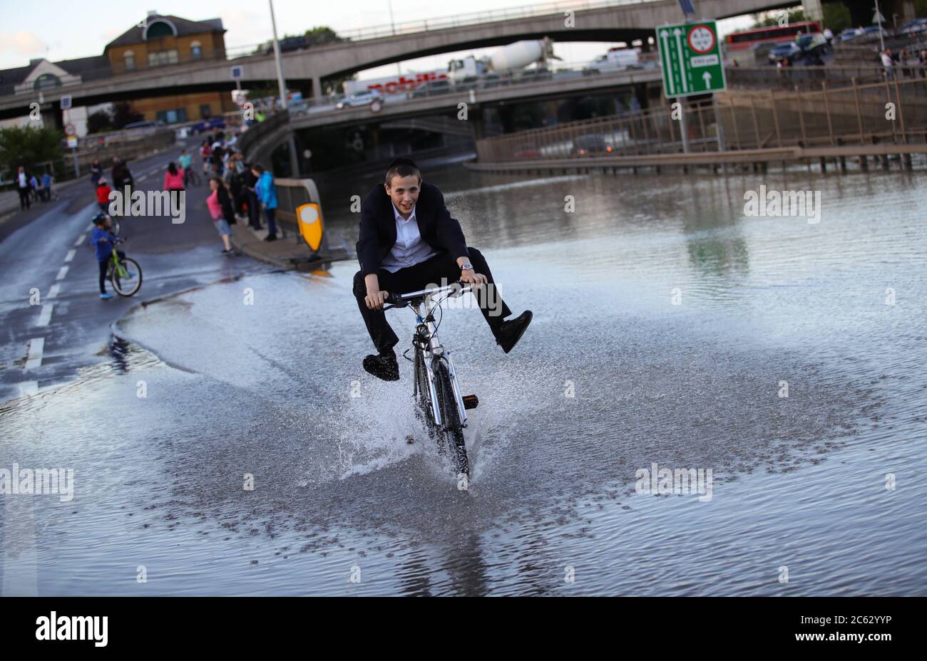 Ein Junge fährt nach einem Wasserausbruch auf der North Circular Road bei Brent Cross, im Norden Londons, mit dem Fahrrad im Flutwasser. Stockfoto