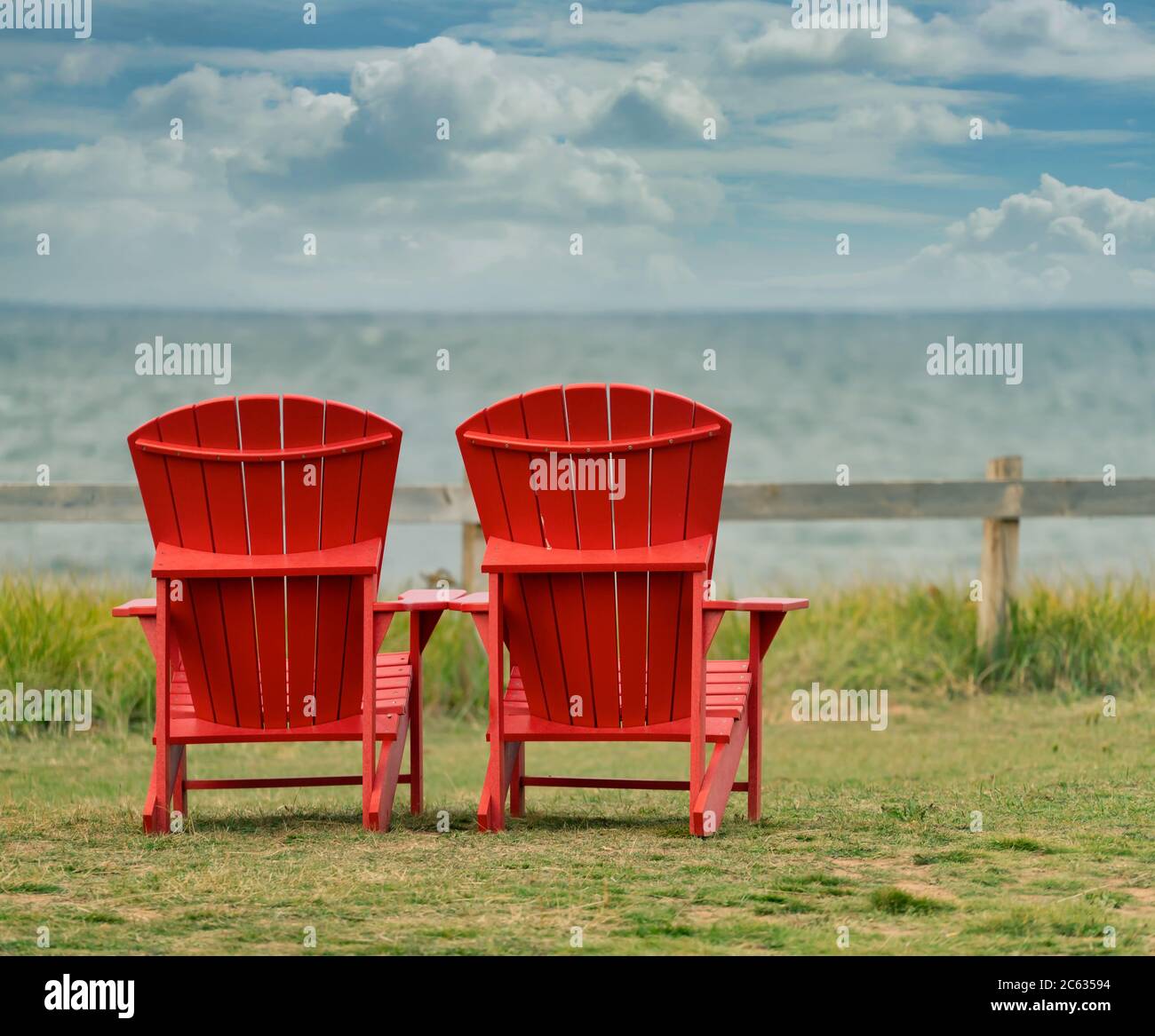 Zwei rote Adirondack-Stühle mit Blick auf das Meer im PEI-Nationalpark, Prince Edward Island. Stockfoto