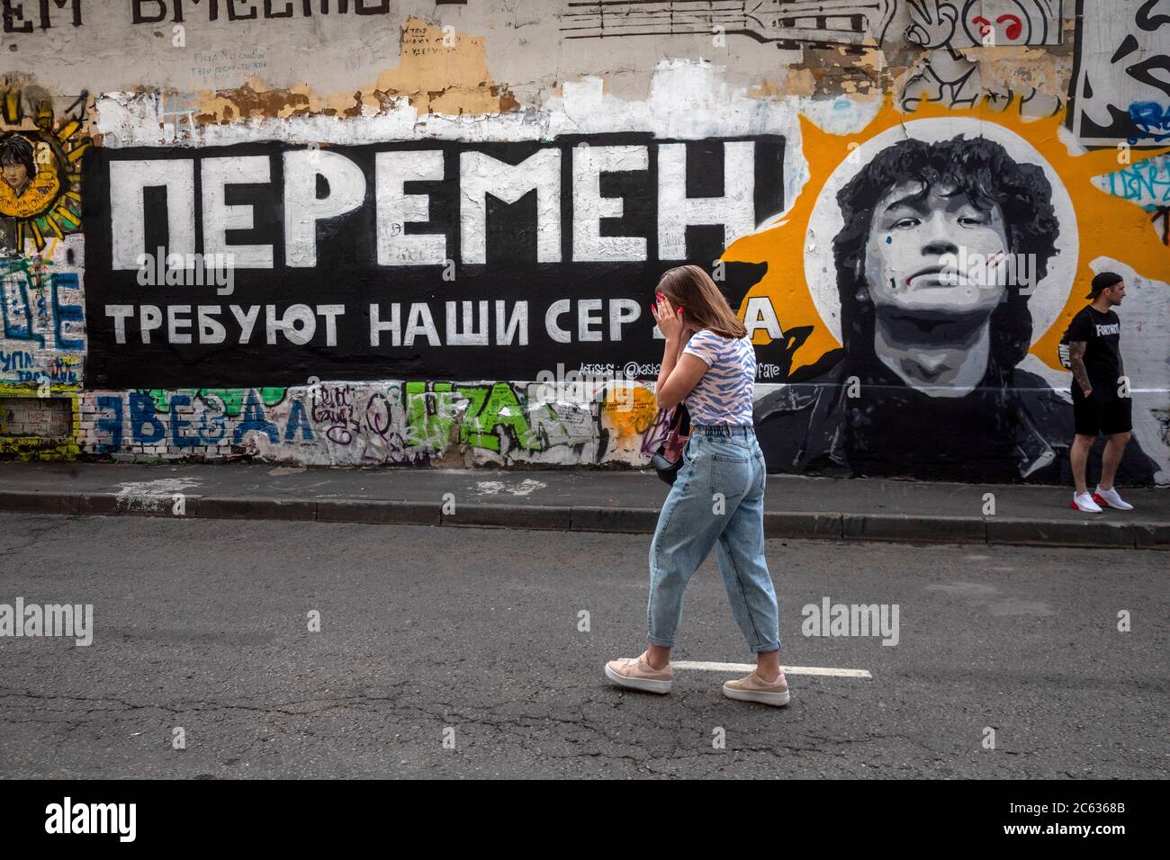 Moskau, Russland. 5. Juli 2020 Menschen nehmen Selfies gegen eine Tsoi-Mauer mit Porträt des berühmten Sängers und Dichters Viktor Tsoi auf Arbat Straße in Moskau, Russland. Viktor Tsoi, Anführer der Rockband Kino, ist bei vielen Russen nach wie vor ein sehr beliebter Rocksänger. Die Worte aus dem berühmten Lied "Peremen" (Veränderung) an der Wand lauten wie "Unsere Herzen fordern Veränderung" Stockfoto