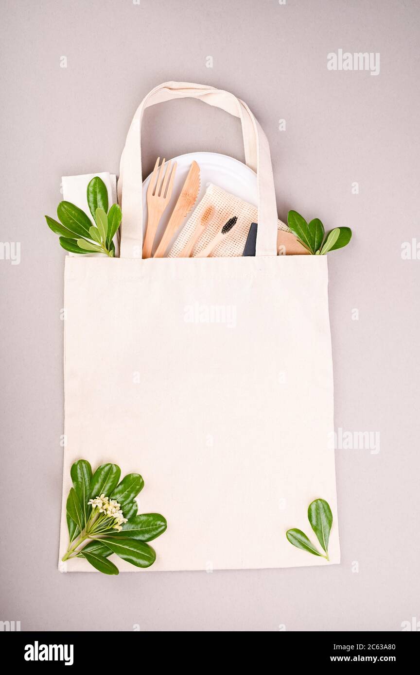 Öko-Beutel aus Baumwolle. Clipping-Pfad. Textil Stoff Kundenpaket Modell Vorlage. Wiederverwendbar für Verbraucher. Tragetasche aus recyceltem Material. Zahnbürsten aus Holz, Papiergeschirr, grüne Blätter. Speicherplatz kopieren. Stockfoto