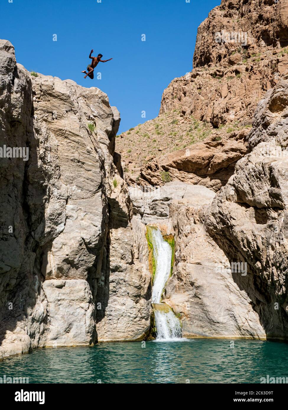 Junger Mann springt in die natürlich geformten Schwimmbäder in Wadi Bani Khalid, Sultanat von Oman. Stockfoto