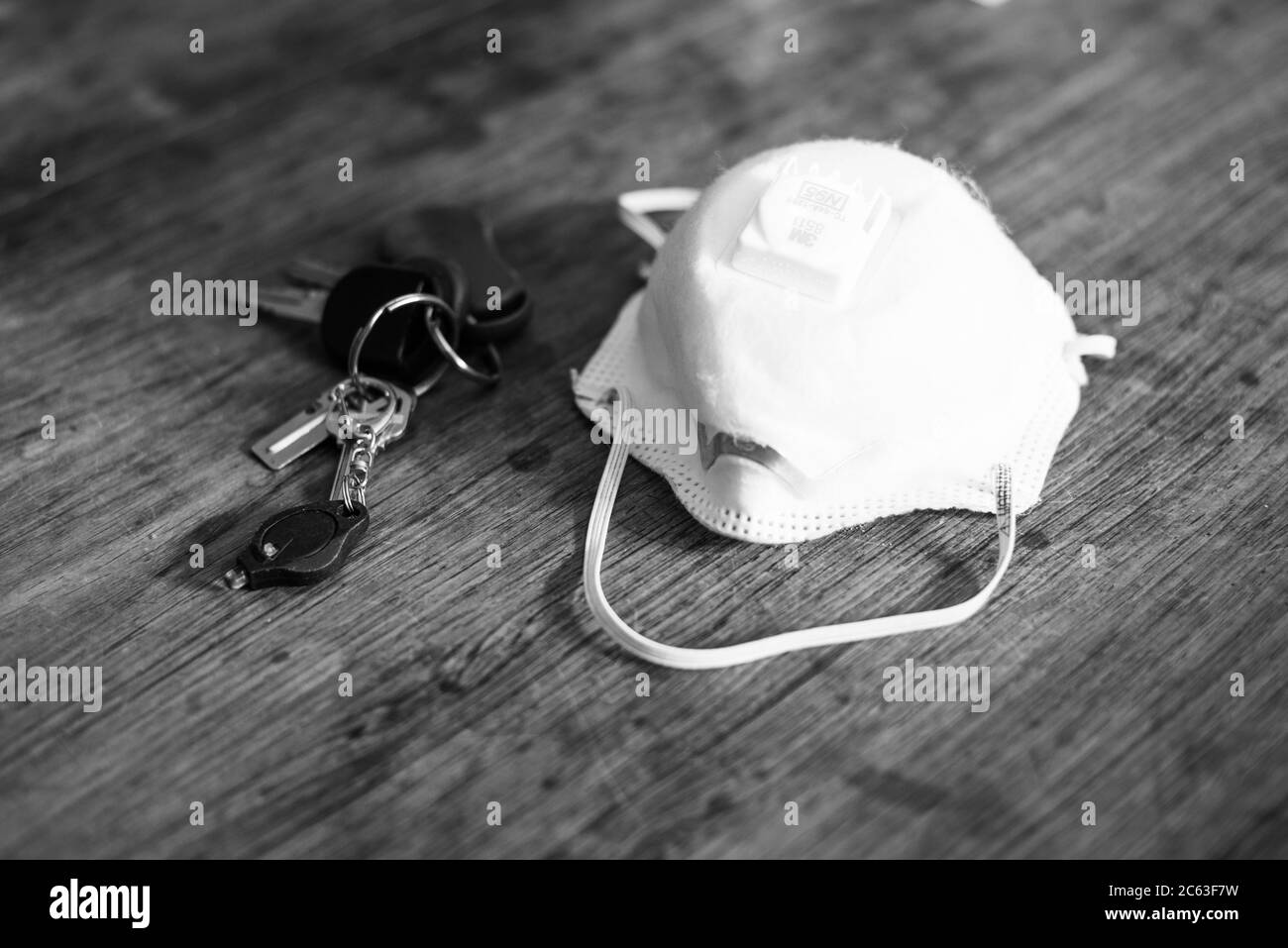 N95 Gesichtsmaske auf dem Tisch zusammen mit Haus- und Autoschlüssel während der Coronaepidemie Stockfoto