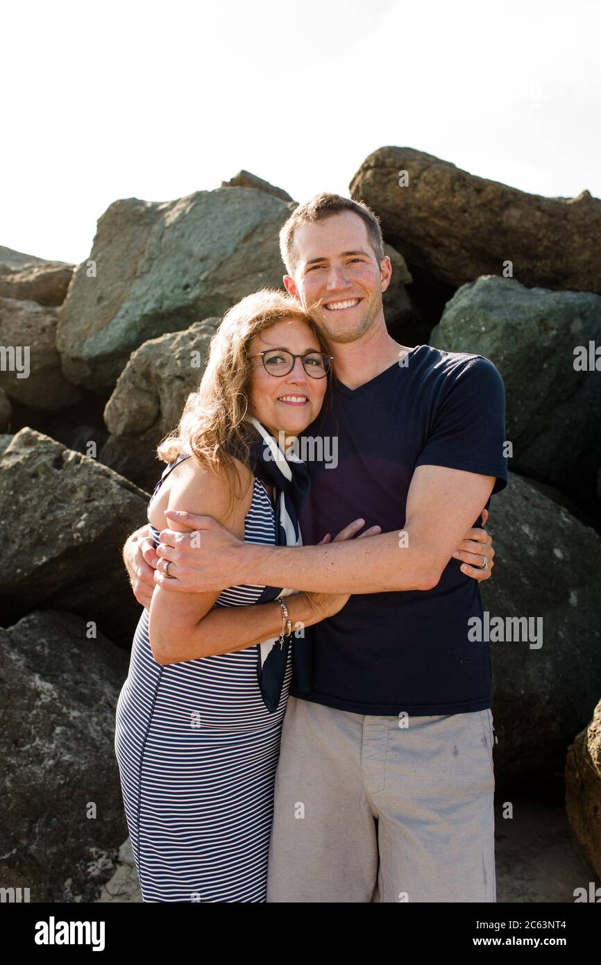 Mutter und Sohn umarmen und lächeln für Kamera am Strand Stockfoto