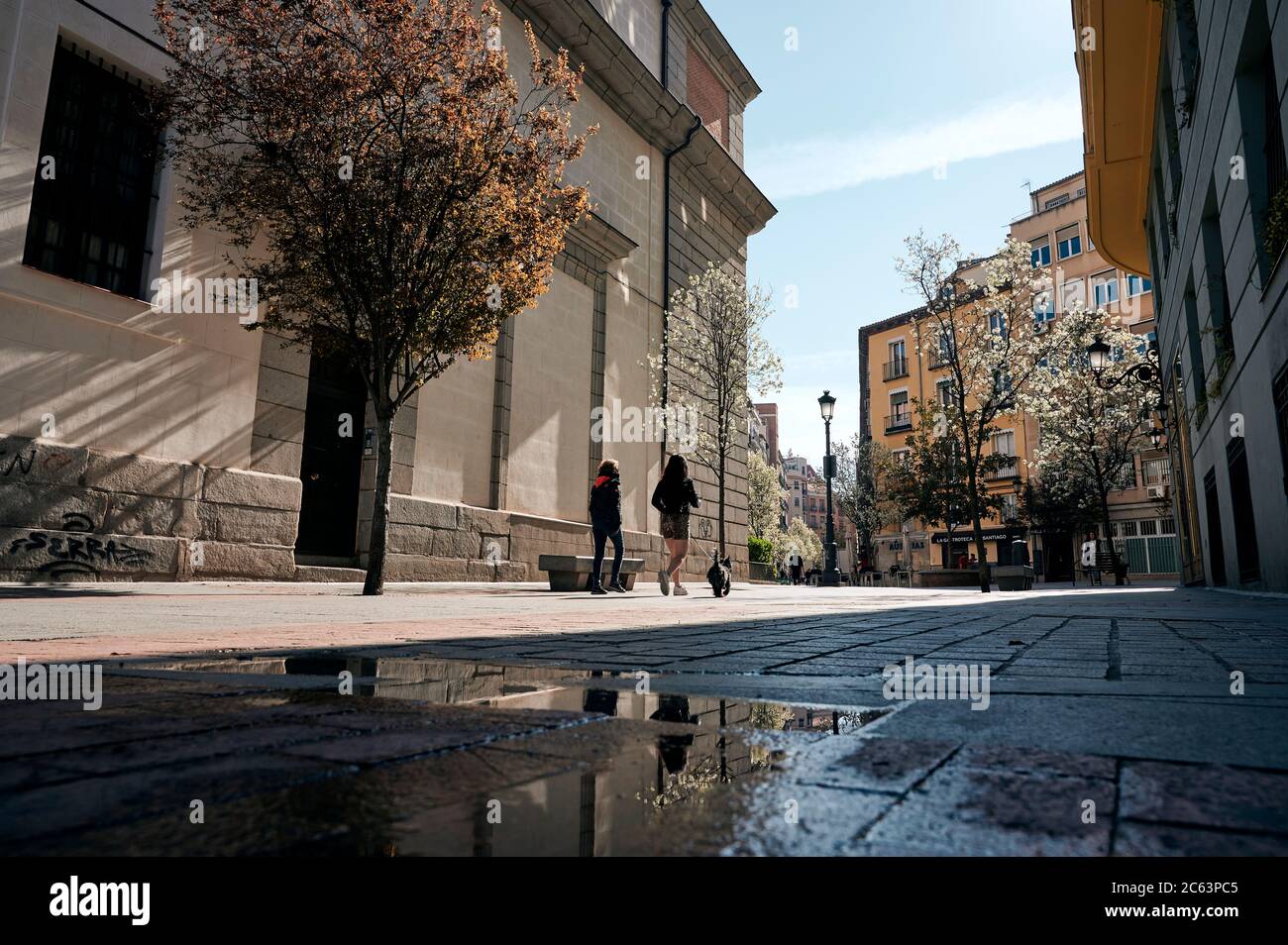 Niedriger Winkel Rückansicht von unkenntlichen Frauen, die an sonnigen Tagen in Madrid entlang der Straße mit Steingebäuden spazieren Stockfoto