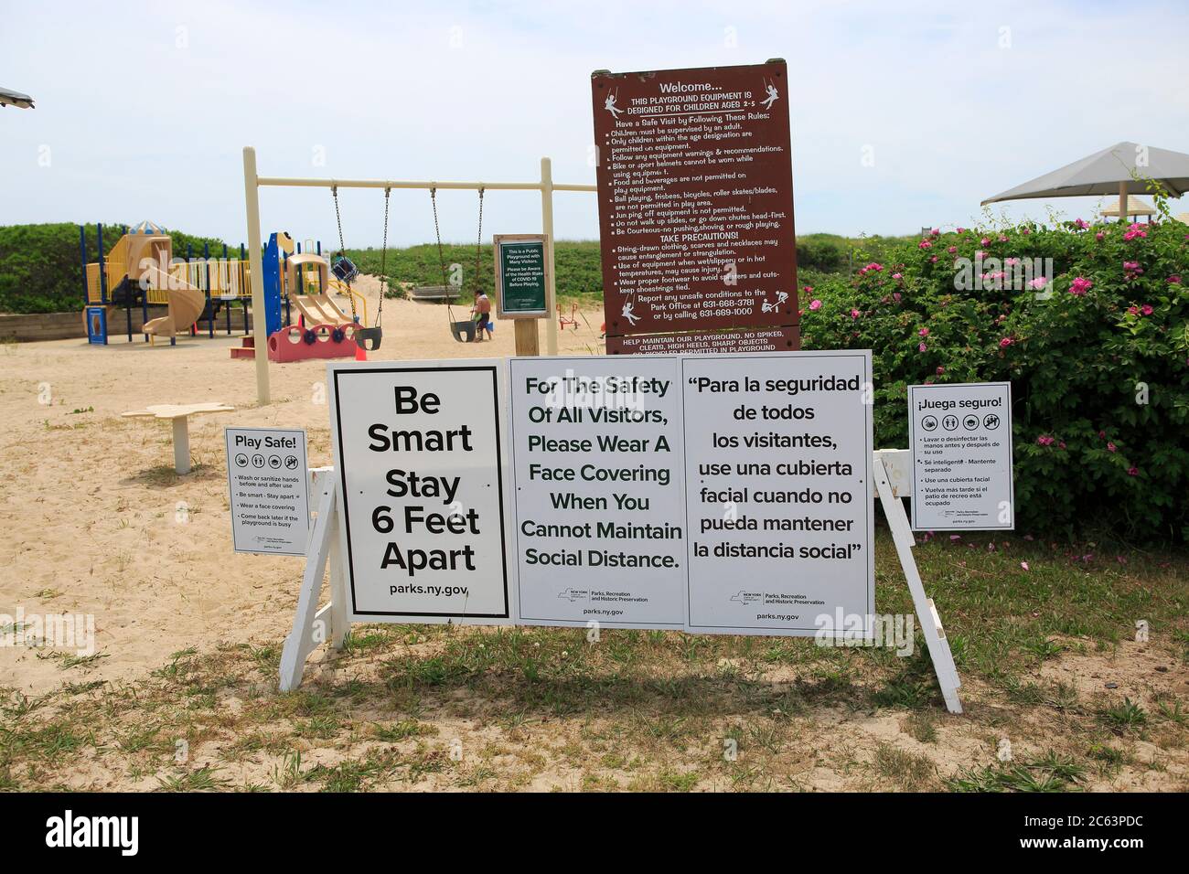 Hither Hills State Park, Strand, Schild auf Spielplatz Warnung Menschen zu sechs Fuß auseinander zu halten, waer maskm Praxis soziale Distanzierung, um die Ausbreitung von Coronavirus COVID-19, hither Hills, Montauk, Long Island, New York, USA zu verhindern Stockfoto