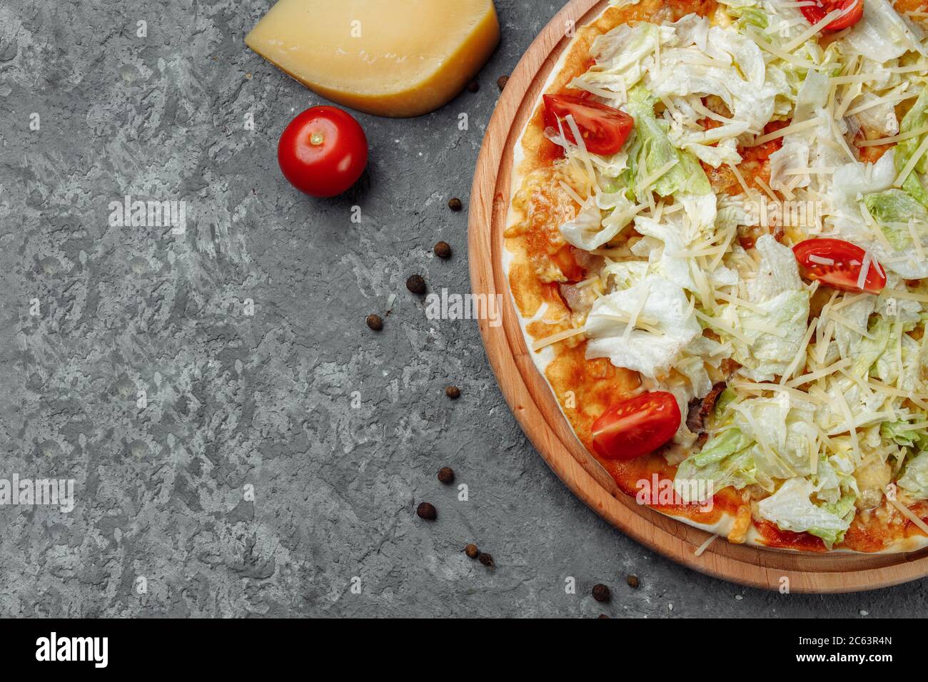 Leckere Pizza im Caesar-Stil mit weißer Sauce, Huhn, Parmesan, Ei, Kirschtomaten und frischem Salat auf Holzhintergrund Stockfoto