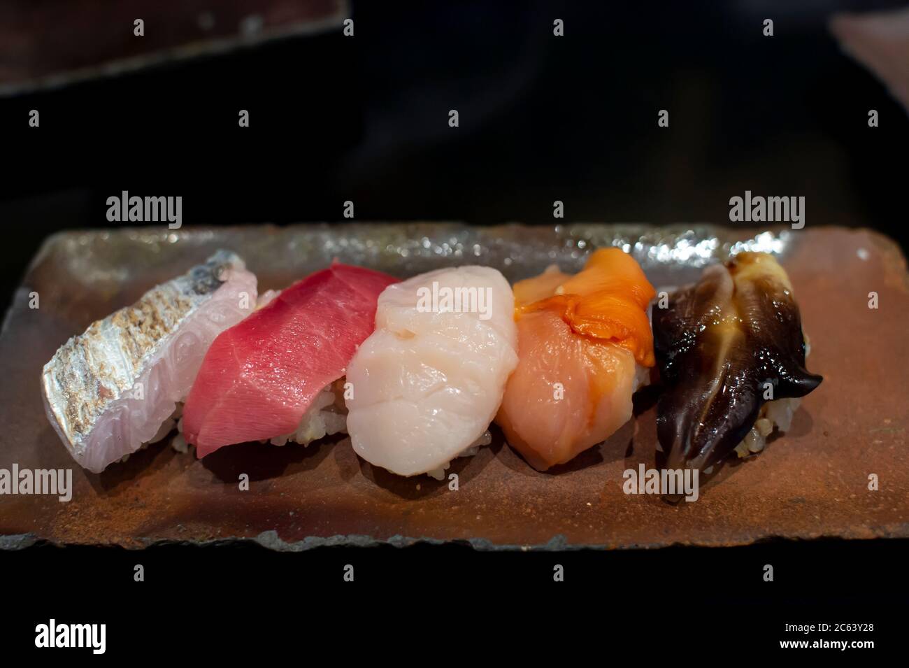 Das Premium Sushi Set wird auf einem schwarzen Steinteller platziert. Ansicht von oben, dunkles Bild. Stockfoto