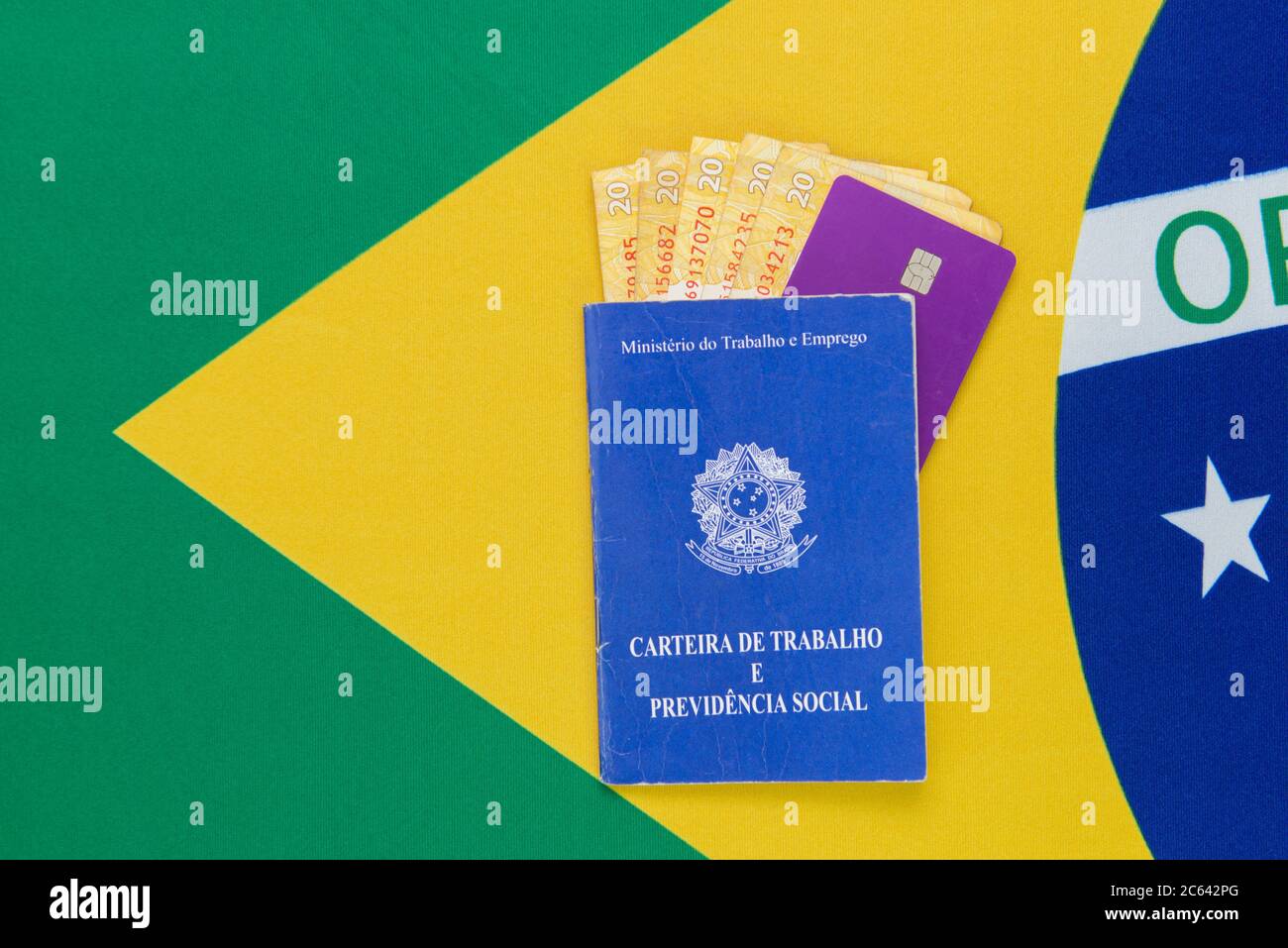 Draufsicht auf brasilianischen Pass mit Bargeld und Kreditkarte innen auf brasilianische Flagge im Hintergrund. Reisekonzept. Einwanderung und Auswanderung, Touri Stockfoto