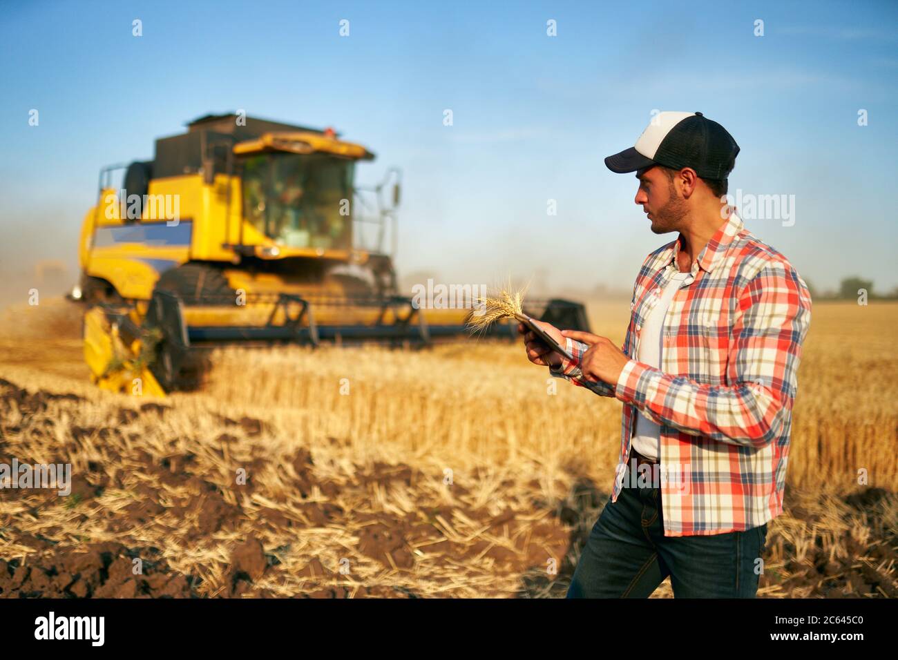 Präzisionslandwirtschaft. Landwirt hält Tablet für Mähdrescher Führung und Steuerung mit modernen Automatisierungssystem. Agronom mit Online-Daten Stockfoto