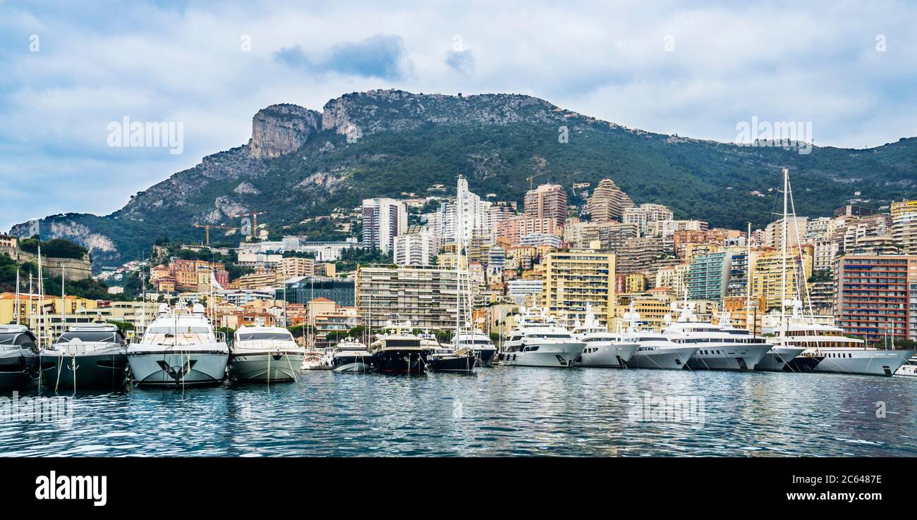 Die Luxusyachten des Port Hercules stehen vor dem Hintergrund des Felsvorgebirges Tête de Chien (Dog's Head), der über Monaco, Fürstentum, ragt Stockfoto