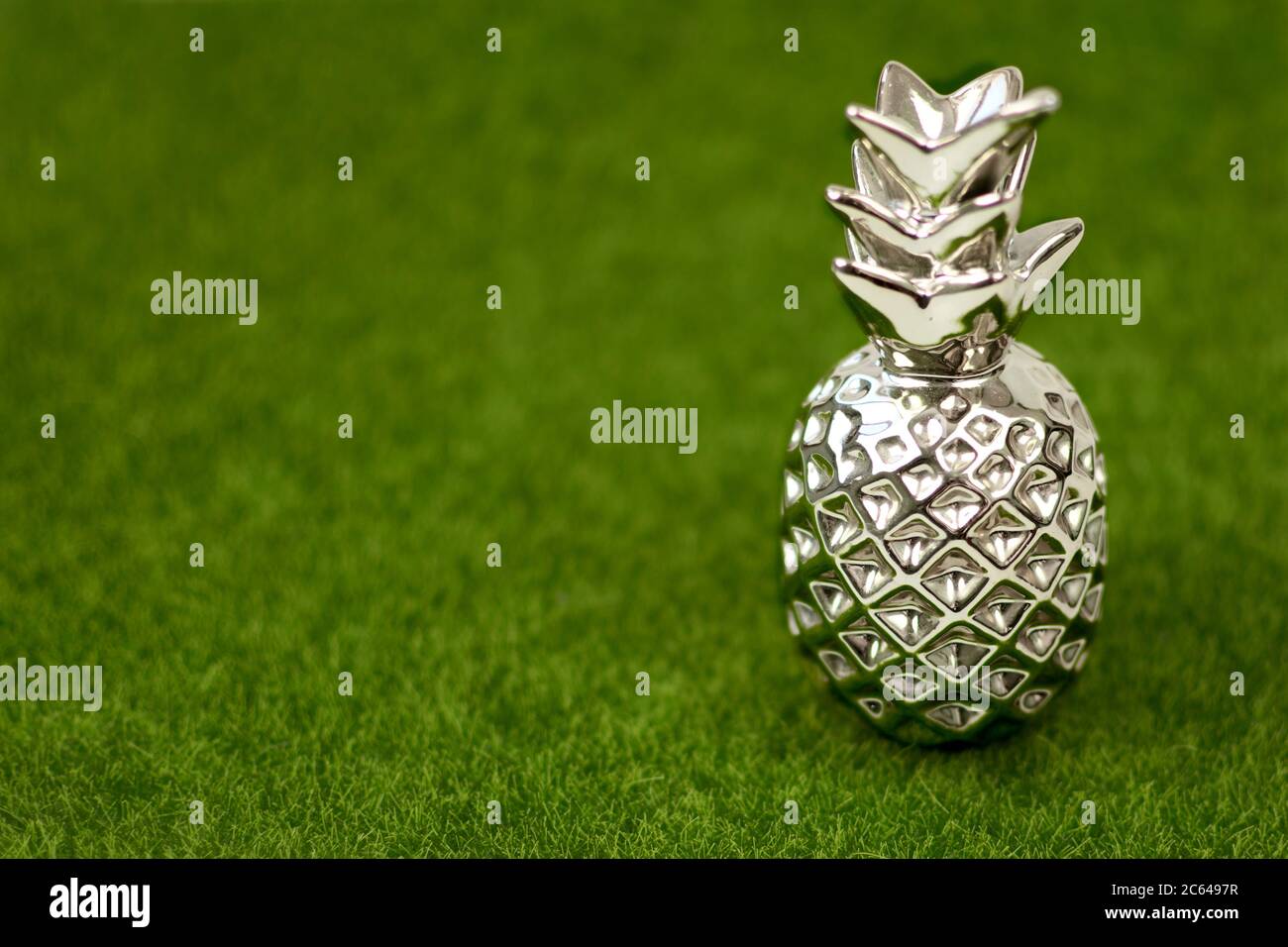 Goldene Ananas mit stilvollem Dekor auf grünem Gras Hintergrund. Silber und Gold Wohndekorationen. Copyspace. Stockfoto