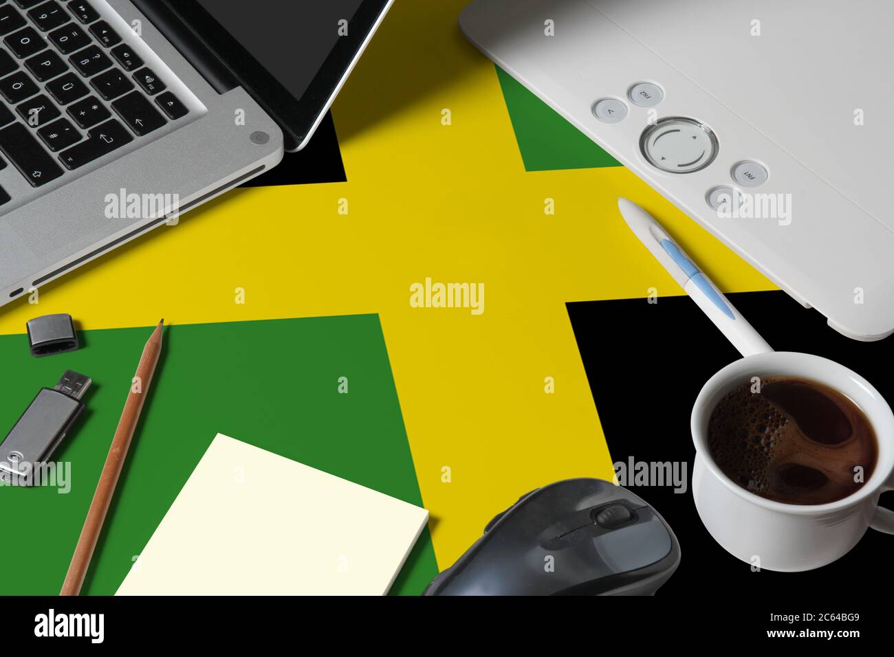 Jamaika Nationalflagge auf der Oberseite Ansicht Arbeitsplatz des kreativen Designers mit Laptop, Computer-Tastatur, usb-Laufwerk, Grafik-Tablet, Kaffeetasse, Maus auf Holz Stockfoto