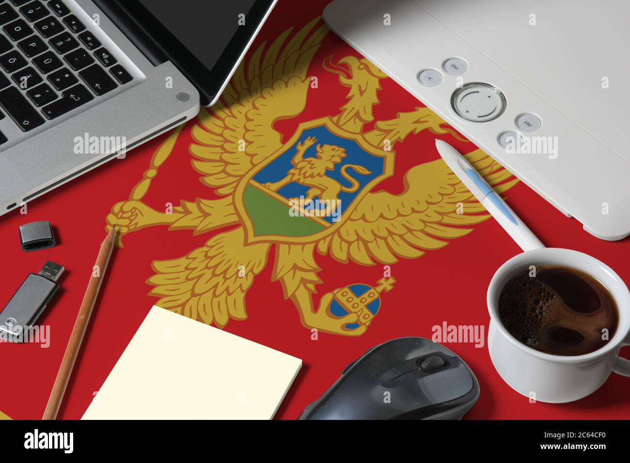 Montenegro Nationalflagge auf der Oberseite Ansicht Arbeitsplatz des kreativen Designers mit Laptop, Computer-Tastatur, usb-Laufwerk, Grafik-Tablet, Kaffeetasse, Maus auf w Stockfoto